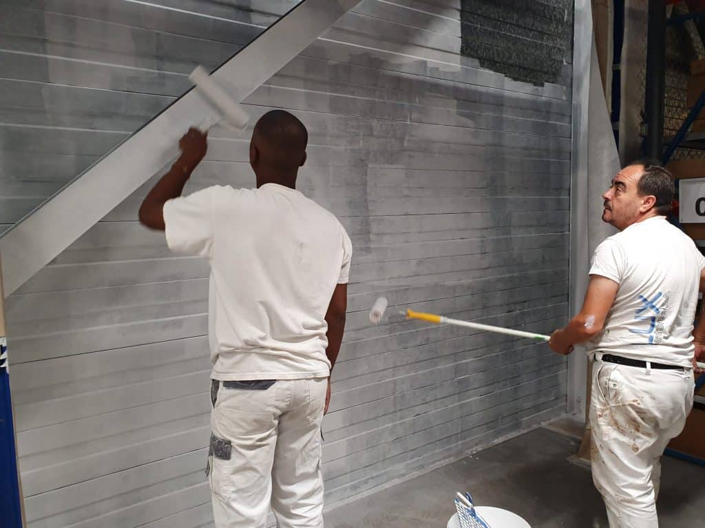 Peintres de Gomes SARL appliquant de la peinture sur une paroi métallique.