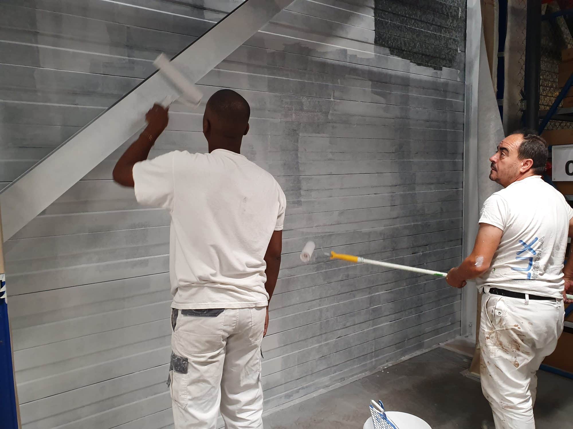 Peintres de Gomes SARL appliquant de la peinture sur une paroi métallique.