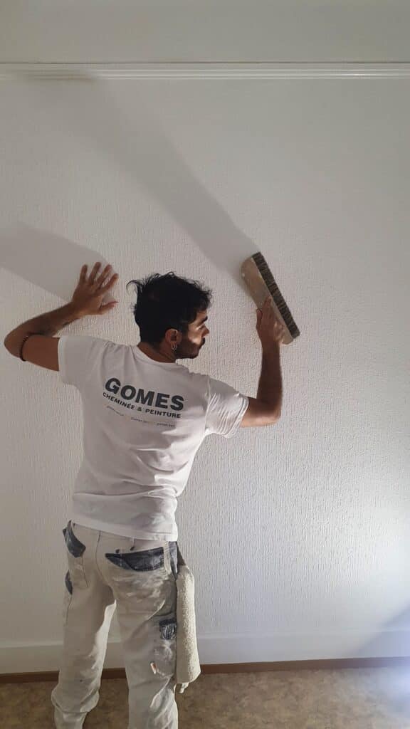 Artisan peintre appliquant de la peinture sur un mur blanc