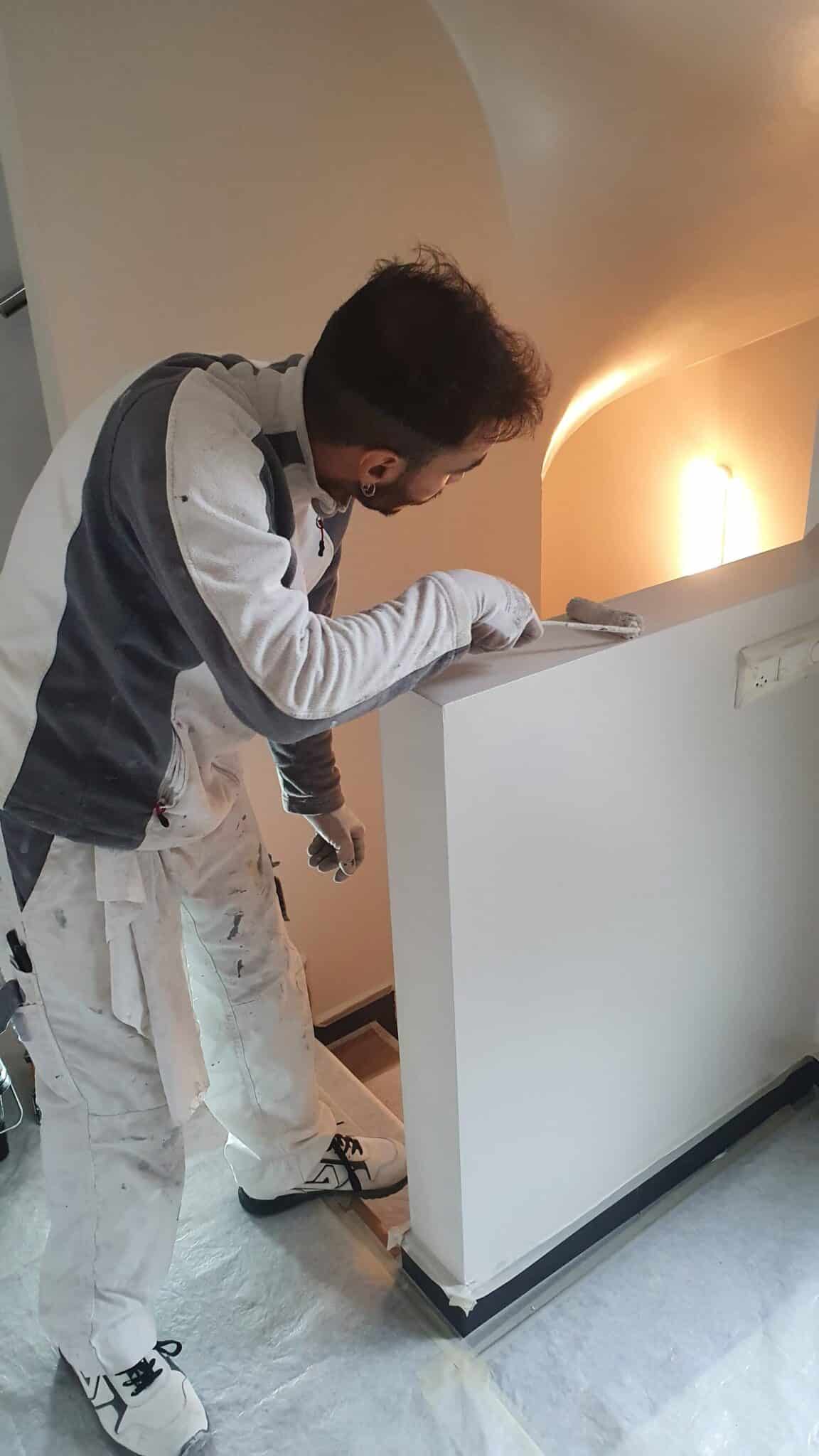 Peintre professionnel de Gomes SARL appliquant une finition sur un mur intérieur.
