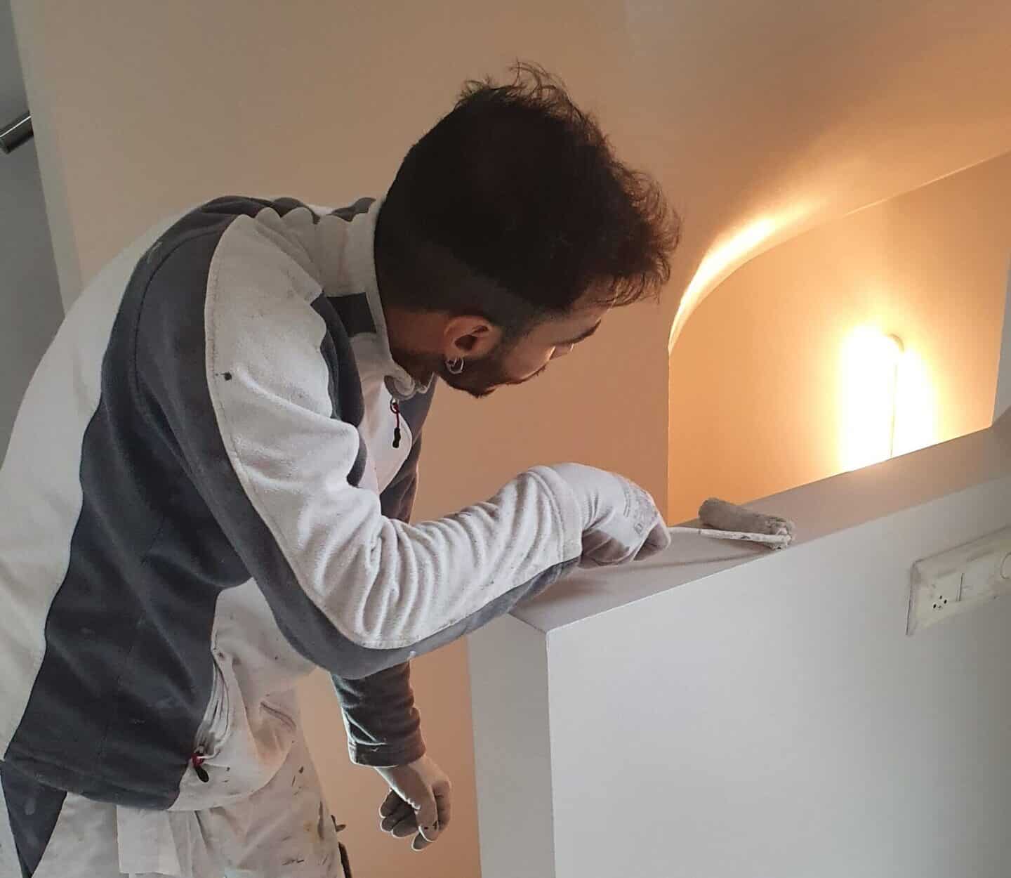 Peintre professionnel de Gomes SARL appliquant une finition sur un mur intérieur.