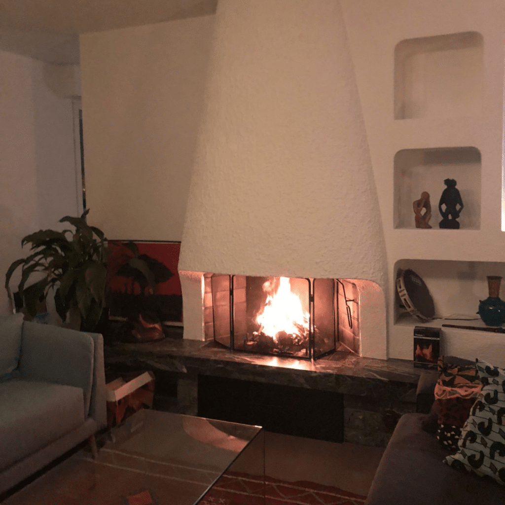 Cheminée moderne en pierre avec foyer allumé dans un salon chaleureux.