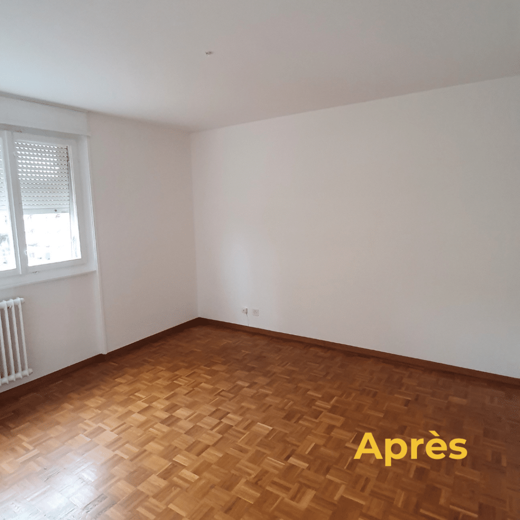 Chambre après rénovation avec murs blancs et parquet au sol.