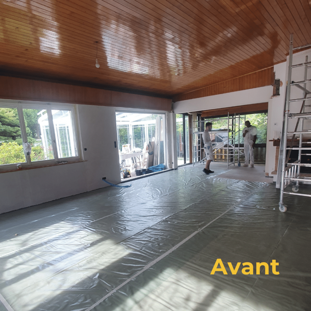 Salle de séjour avant rénovation, avec plafond en bois et bâches de protection.