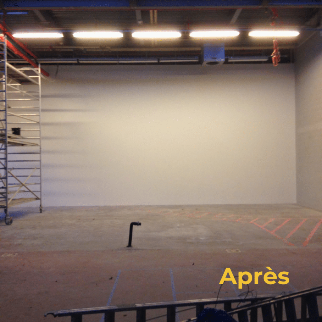 Mur rénové dans un espace industriel avec finition blanche et épurée.